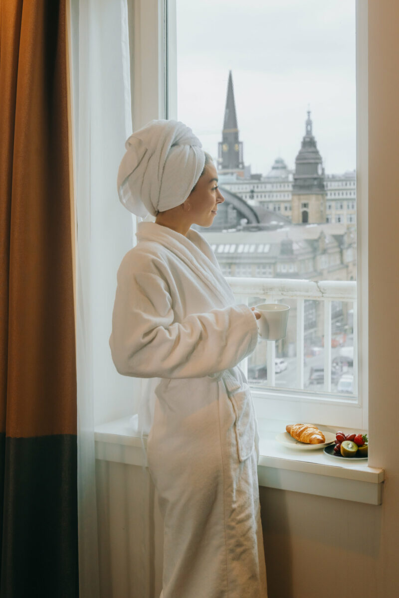 Frau mit Kaffee am Fenster in einem Zimmer des Reichshof Hamburg