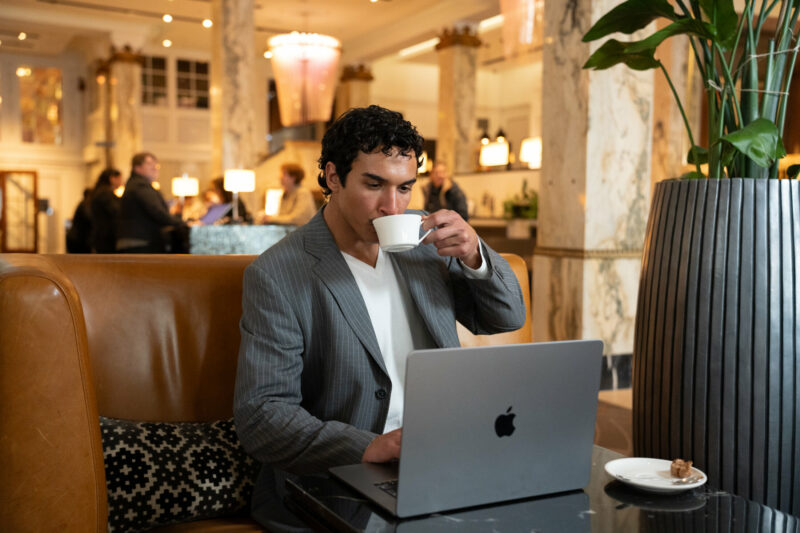 Man in der Lobby am Laptop mit Kaffee
