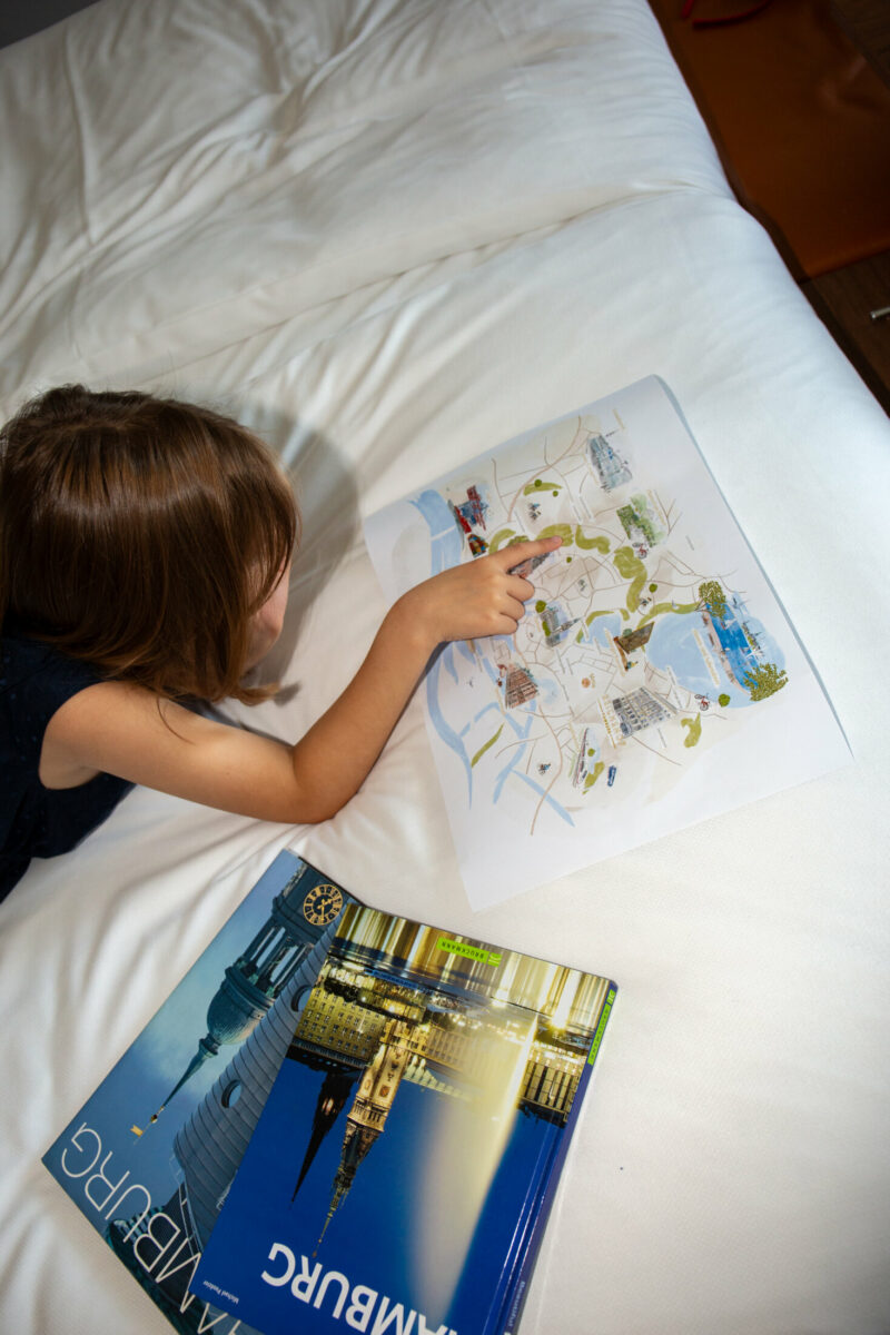 Kind schaut sich Stadtplan an auf dem Bett
